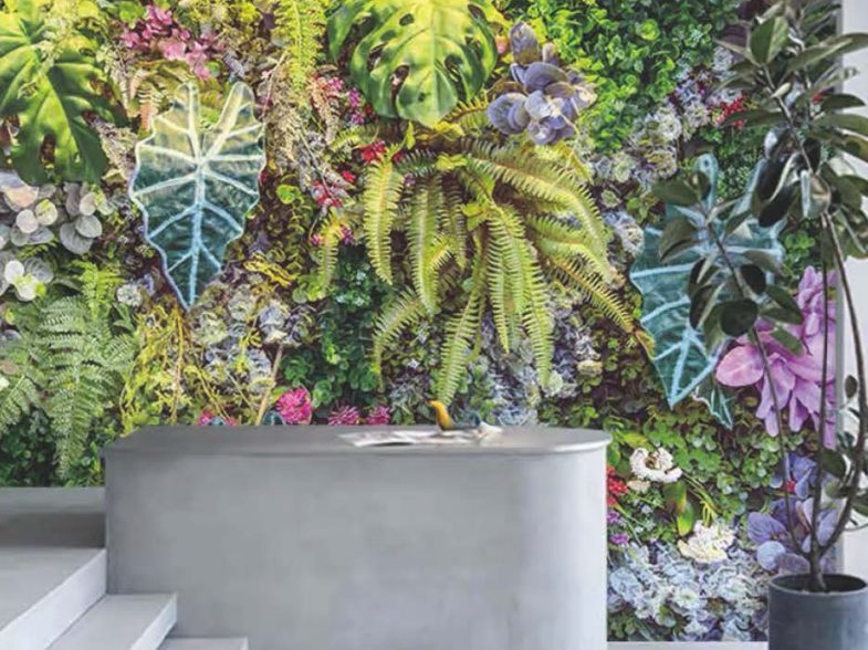 An artificial green wall of ferns, moss and flowering foliage behind a stone bench