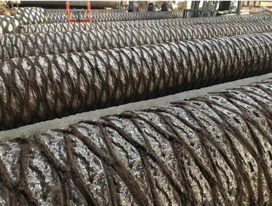 Rows of finished artificial palm trunks with woven scale texture