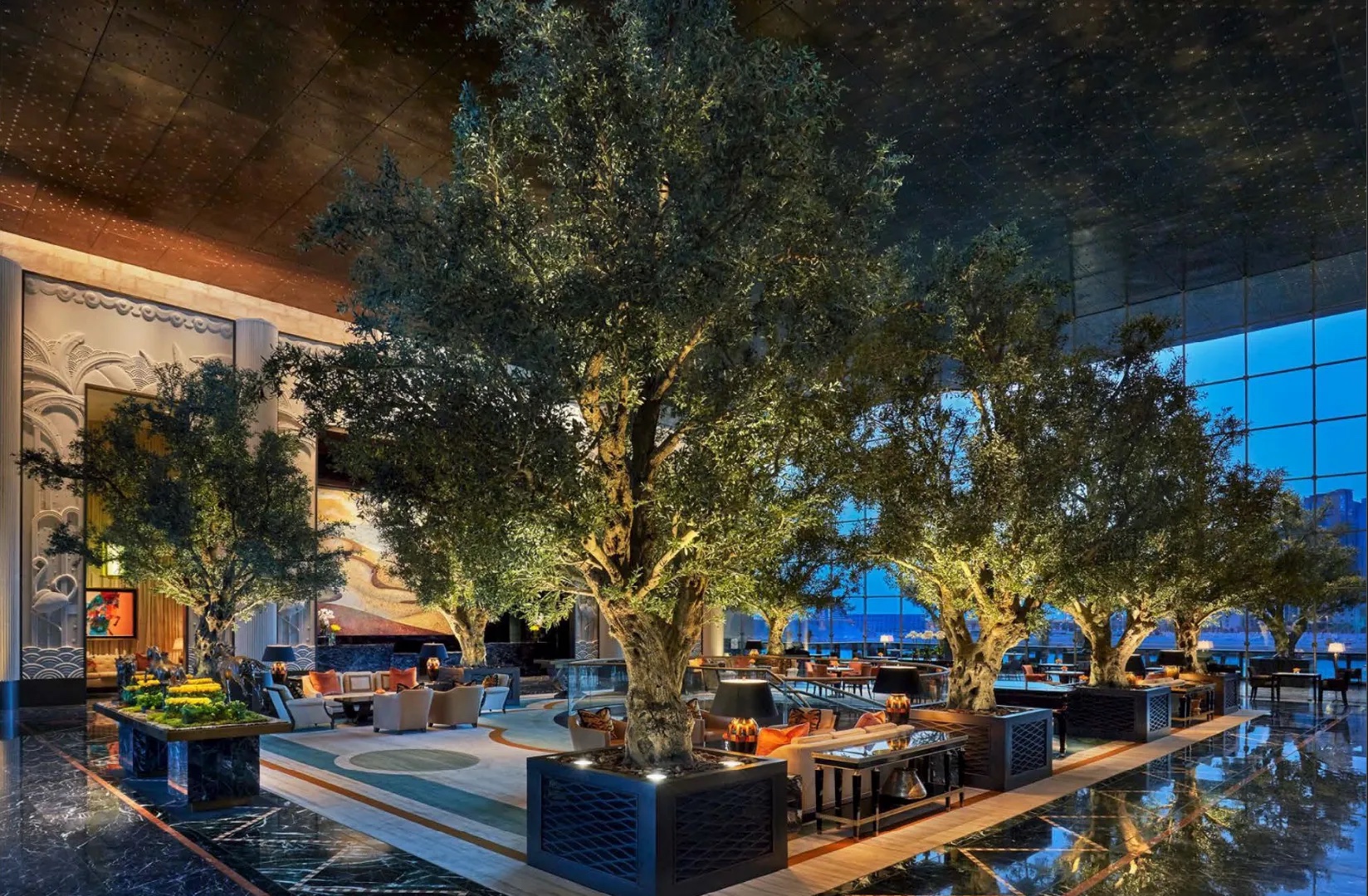 The lobby of Four Seasons Hotel Bahrain Bay, planted with a grove of large artificial olive trees in dark lattice planters