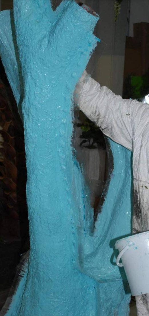 A blue silicone mold being applied over a tree trunk