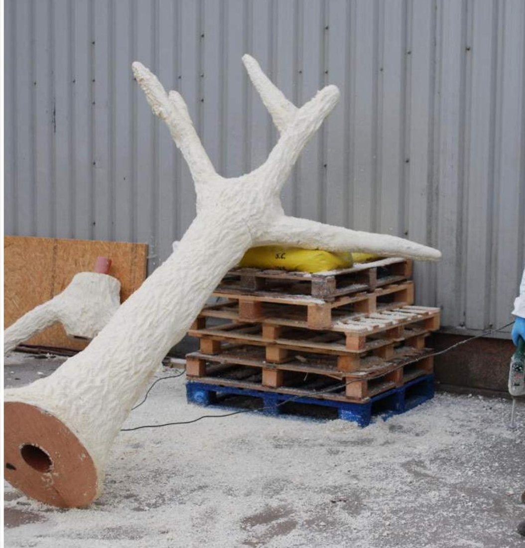 A white branching tree frame resting on a pallet in the workshop