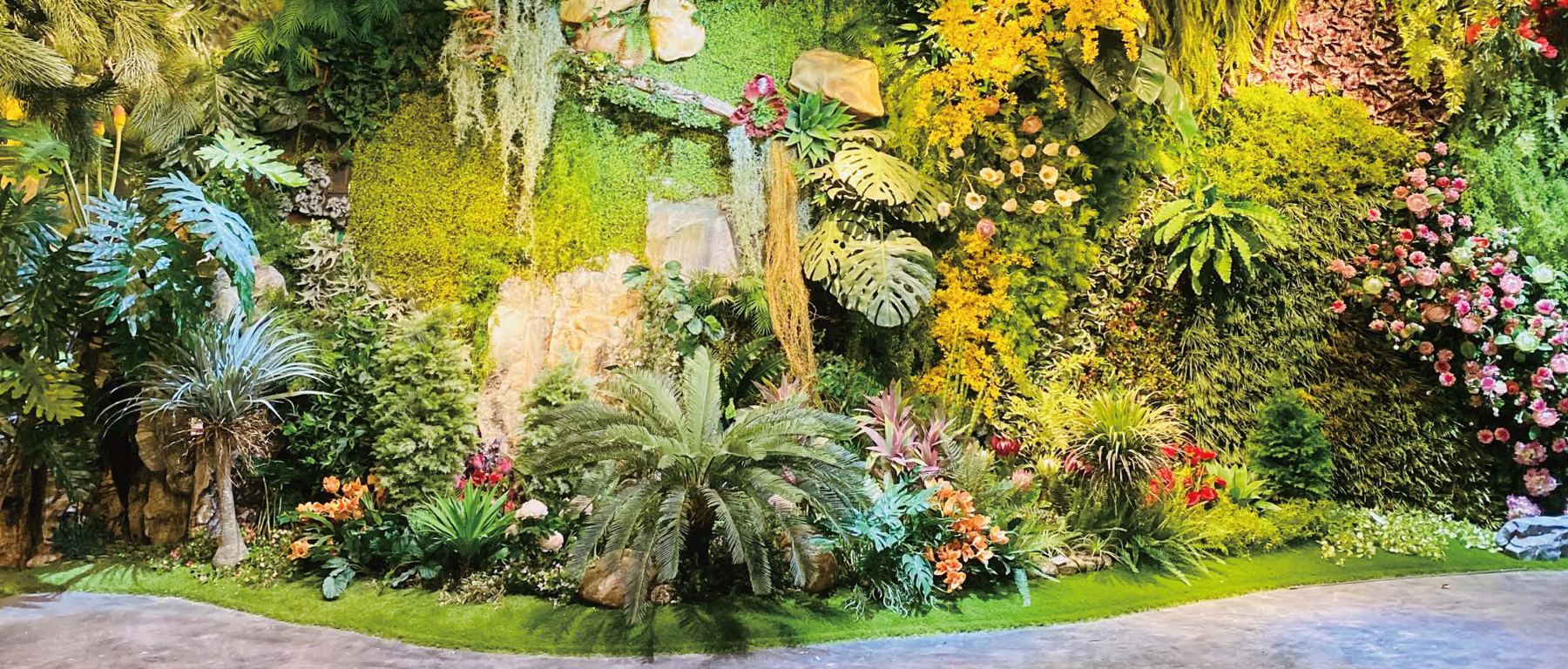 Lush layered planting with palms, ferns and flowers in a showroom