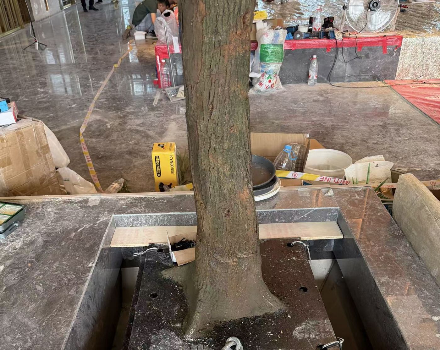 A sculpted trunk fixed into a steel base inside a stone planter